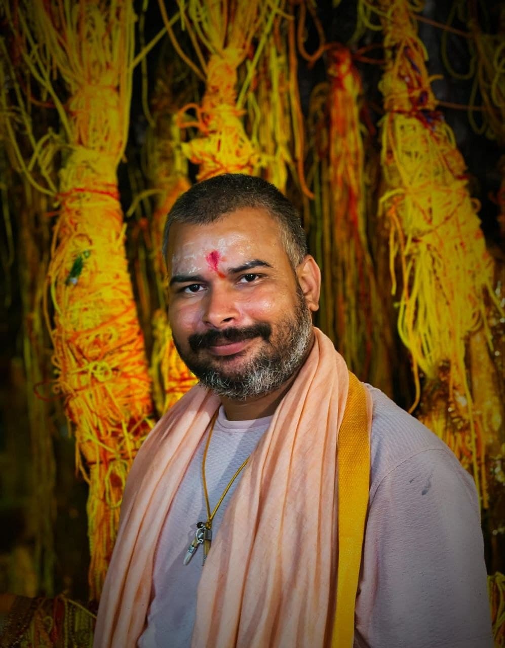 Pandit Ji performing sacred Maa Baglamukhi Havan with burning kund, golden deity in temple background